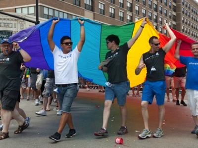 Group of men hoisting large rainbow banner in the Chicago Gay Parade.