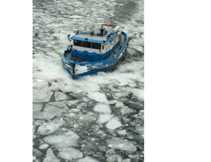 Blue and white boat cutting through ice on the Chicago River.